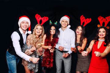 Wall Mural - Party with friends. They love Christmas. Group of cheerful young people carrying sparklers and champagne flutes dancing in new year party and looking happy. Concepts about togetherness lifestyle