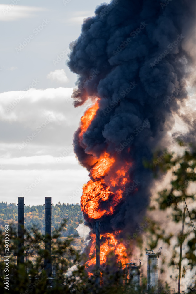 Large fire at an oil refinery. Only parts of the refinery visible ...
