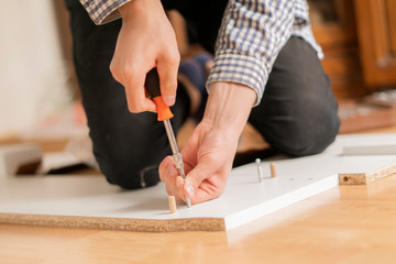 close up man assembling new furniture with a screwdriver b