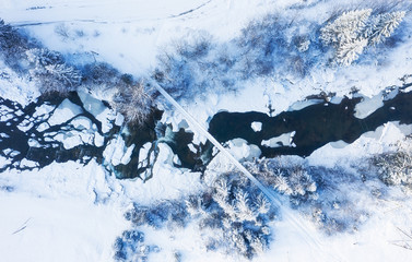 Wall Mural - Aerial view on the river and bridge at the winter time. Natural winter landscape from air. Forest under snow a the winter time. Landscape from drone