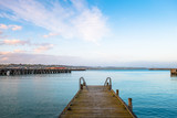 Fototapeta Pomosty - Beautiful sunset at the dock. Blue sky and Ocean with town view. Omaru, New Zealand.