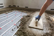 © mmphoto - Screed flooring. Worker at a construction site screed floor.