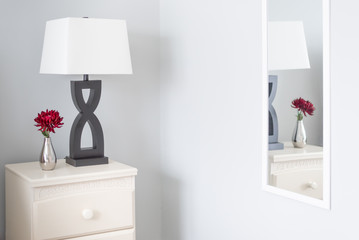 Night stand in bright room with red flower