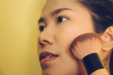 Beauty face of Asian woman by applying brushes and smooth face skin by cosmetics.