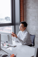 Canvas Print - Portrait of Chinese businessman in white shirt sitting at office desk using computer