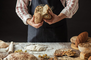 So, break bread with me. Cropped view of male Chef breaking freshly Baked Sourdough Bread, focus on loaf of bread.