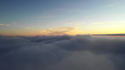 Wall Mural - aerial flight above clouds during golden hour in sunrise light.