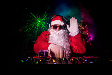 Dj Santa Claus at Christmas with glasses and snow mix on New Year's Eve event in the rays of light.