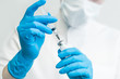 the doctor's hands in blue gloves holding medical syringe and vial for injections from the disease