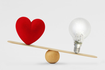 Heart and light bulb on scale - Concept of brain priority over heart in life