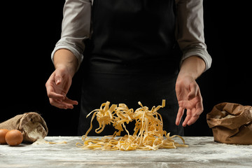 Cooking spaghetti, italian pasta, pasta on a black background. Frost in the air with flour particles. Food banner, large resolution.