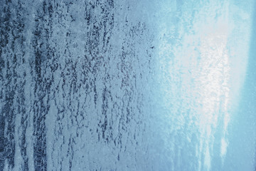 Frozen winter window pane coated shiny icy patterns. Frost background, closeup. Extreme north low temperature. Natural ice glass