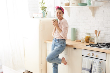 Young woman drinking a morning coffee in kitchen
