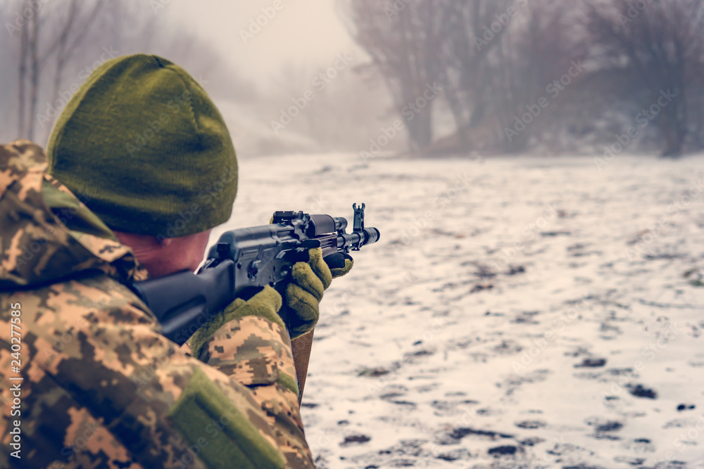 A military soldier with a Kalashnikov assault rifle conducts aimed fire ...