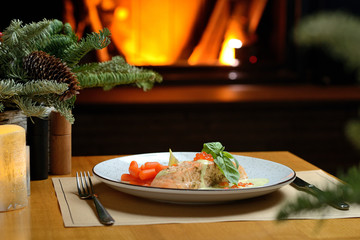 Wall Mural - salmon fillet with carrots, basil and red caviar, against the background of the Christmas tree and fireplace