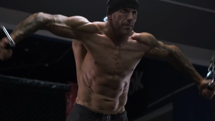 adult male athlete with tattoos on his arms exercising in the gym.