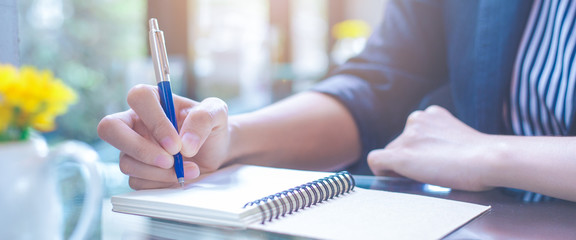 Business woman writing on a notebook.with a pen in the office