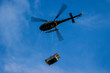 Helicopter with blurred blades carrying loads flying against the blue sky