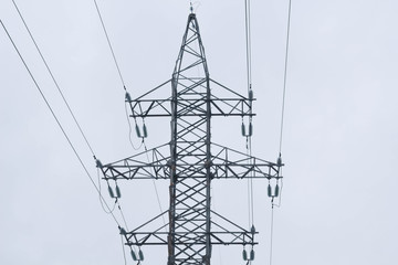 a high voltage power pylons against blue sky and sun rays