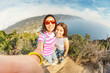 Happy friends tourists are enjoying seascape view and taking selfie together in Cinque Terre, Italy