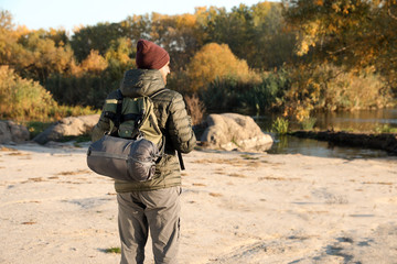 Wall Mural - Male camper with backpack and sleeping bag in wilderness. Space for text