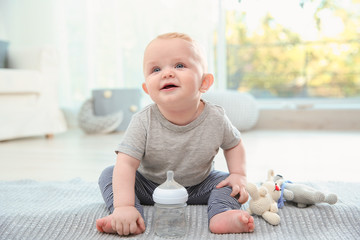 Wall Mural - Cute baby with bottle sitting on floor in room