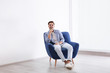 © New Africa - Handsome young man sitting in armchair indoors