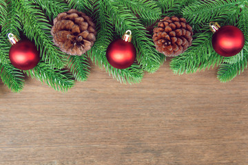 Wall Mural - Christmas background. Fir tree branches, red Christmas ball and pine cones with decoration on a wooden board. with copy space for text.