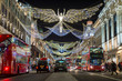 Red double-decker buses pass under twinkling Christmas lights along the upscale shopping district of Regent Street.
