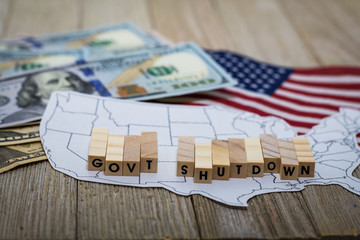 Government Shutdown USA concept with American flag and money bills on white background and wooden board