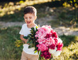 © teksomolika - Small boy carries a large bouquet of peonies.