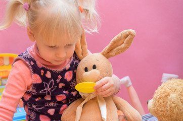 The little girl is playing with any soft toys.