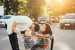 © teksomolika - Young parents put their son in a cart and have fun in the parking.