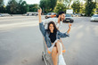 © teksomolika - Handsome guy carries his girlfriend in cart in the parking lot
