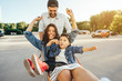 © teksomolika - Young dad carries mom and son in a cart on the parking lot
