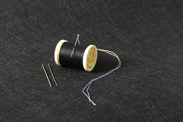 Wall Mural - sewing needle and rope reel, on black background,