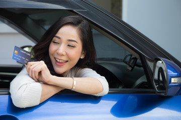 Happy young Asian woman holding payment card or credit card and used to pay for gasoline, diesel, and other fuels at gas stations, Driver with fleet cards for refueling car