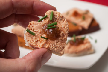 closeup of foie gras on bread in shaped heart in hand on festive table background