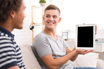 Happy guy showing digital tablet with blank screen