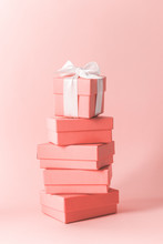 Close View The Stack Of Boxes Tied With Silk Ribbon, Lying On Each Other On Living Coral Color Pastel Background. Gift Festive Selection.