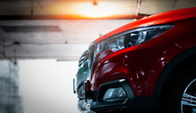 Selective Focus On Red Shiny SUV Sport Car Parked At Shopping Mall Indoor Parking Lot. Headlamp Lights With Elegant And Luxury Design. Automotive Industry And Hybrid Car Concept. Underground Parking.