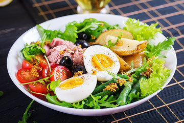 Wall Mural - Healthy hearty salad of tuna, green beans, tomatoes, eggs, potatoes, black olives close-up in a bowl on the table. Salad Nicoise. French cuisine.