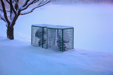 Street electric floodlights in winter covered with a snow-covered grille.