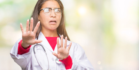 Sticker - Young arab doctor woman over isolated background afraid and terrified with fear expression stop gesture with hands, shouting in shock. Panic concept.