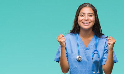 Sticker - Young arab doctor surgeon woman over isolated background celebrating surprised and amazed for success with arms raised and open eyes. Winner concept.