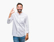 Adult hispanic man over isolated background smiling positive doing ok sign with hand and fingers. Successful expression.
