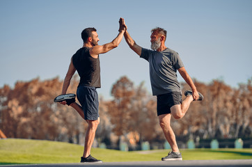 Wall Mural - The young and old athletes stretching in the beautiful park