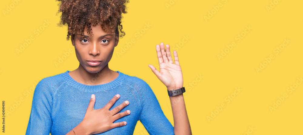 Beautiful young african american woman over isolated background Swearing with hand on chest and open palm, making a loyalty promise oath - obrazy, fototapety, plakaty 