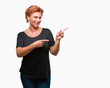 © Krakenimages.com - Atrractive senior caucasian redhead woman over isolated background smiling and looking at the camera pointing with two hands and fingers to the side.