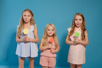 three girlfriends sisters eat sweet lollipop with sweet chocolate dessert